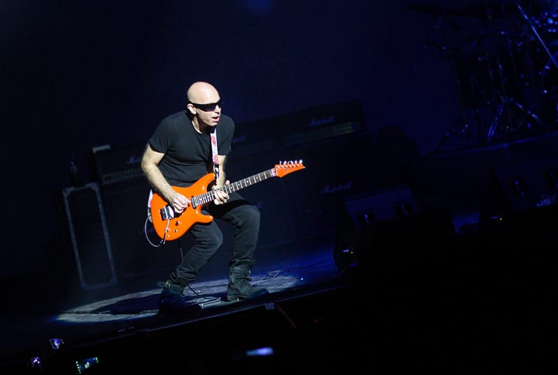 Joe Satriani volvió a la Argentina - Joe Satriani sabe de rock n' roll. Porque Joe Satriani no solo toca la guitarra, no solo ejecuta frases y ligados imposibles haciéndolos parecer la actividad humana más sencilla. No. Joe Satriani es quizás el único guitarrista de los llamados 'virtuosos' que ha logrado que sus piezas sean canciones: simples (y complicadas) canciones en las que esa guitarra que hace las veces de melodía principal puede ser, en cualquier momento, reemplazada por una voz cantante que probablemente transmitirá con palabras exactamente las mismas sensaciones que Satriani logra transmitir con su tenue caricia sobre las cuerdas. satriani