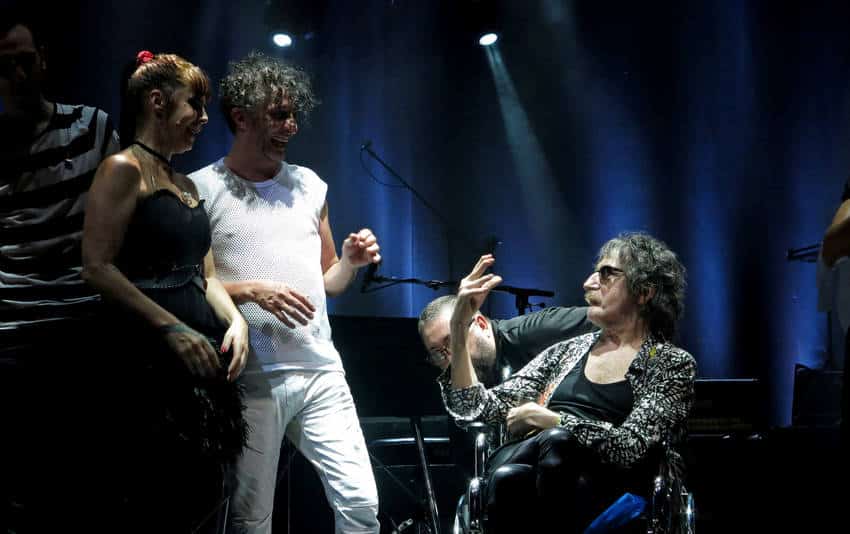 Gran cierre de Fito Páez en su ciclo "Giros", con Charly García como invitado - Fito Páez clausuró anoche su serie de recitales de celebración de los 30 años de su disco "Giros", ante y con un Gran Rex repleto, con un desempeño en el que la precisión de una banda impecable al servicio de una lista que incluye a no pocas de las canciones que ocupan el podio del repertorio del rock argentino, y la emoción se complementaron de la mejor manera. Y con la presencia de un Charly García animado, y coronado por el público como la estrella de la noche.
Como ya fuera consignado al comienzo de la serie, a fines del mes pasado, el repaso que Páez popuso de su producción de los '80, con foco en esa especie de El amor después del amor con pocos recursos que es "Giros", donde el rock, el folclore, el tango, el punk y el pop conviven en 35 minutos sin un segundo de desperdicio, actualizó un catálogo que no resistió, sino que superó el paso del tiempo sin inconvenientes.
"Folis Verghet", "Fue amor", "Canción sobre canción", "Tres agujas", "Nunca podrás sacarme mi amor", "Pompa Bye Bye/De 1920", "Hay otra canción", "Dame un talismán", "Lejos de Berlín", entre una treintena de títulos que no perdería brillo si fueran reemplazados por los que quedan fuera de la arbitraria enumeración.
Pero el retrato implacable según el rosarino de esa época de ebullición permanente no se agotó esta vez en su testimonio. Tras el conmovedor mantra en que el paso del tiempo transformó a Y dale alegría a mi corazón, el centro de la escena -detrás de los teclados, de calzas, sombrero de ala angosta y silla de ruedas-, fue para Charly García. Entonces, Páez y los suyos asumieron el papel de banda de apoyo para que Say No More pudiera transitar "Yendo de la cama al living" y "Necesito tu amor" de la mejor manera que hoy puede hacerlo: desprolijo, visceral, errático y sin disfraz, respaldado por la sala a pleno.
Y estuvo bien. Como también lo estuvo cuando la pelota volvió al campo del rosarino, con una versión incendiada de "Ciudad de pobres corazones". "Esto es rock", sentenció después del último acorde, García. "Sin él, no seríamos nada", lo mimó el dueño de casa. "Mirá que lindo, Fito", retrucó el invitado, con la guitarra en su regazo y señalando los miles de celulares que iluminaban la sala, con sus luces totalmente apagadas y con "Brillante sobre el mic" como banda sonora de un momento único. "Antes eran los encendedores; ¿te acordás?", tiró Páez, mientras en muchos rostros las gotas de transpiración se confundían con las de la emoción. "¡Free Moria!", disparó un rato después Charly, como reporte de actualidad.
El final, fiel al guión, fue con "A rodar la vida" enmarcada en trapos revoleados al aire y algún corpiño de generosa talla volando al escenario, y con la imprescindible "Mariposa Teknicolor" que marca cada fin de fiesta. Aunque esta vez, la despedida fue diferente. Una vez más, el centro del cuadro fue para Charly, ladeado por su discípulo -generoso y agradecido- y por Fabi Cantilo, ambos de rodillas junto a la silla de ruedas, y el resto de los músicos como espectadores a la vez protagonistas de una ovación que fue toda para el invitado; esta vez, más especial que nunca.
Giros-Charly-Garcia-Jose-Mateos_CLAIMA20151221_0059_29